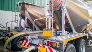 Tanker storage truck loading materials in storage silo at factory.